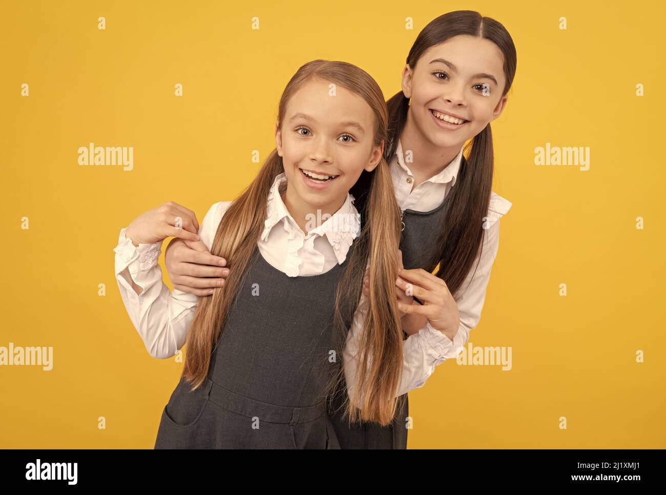 Happy school kids with beauty look wear long hair in formal uniforms yellow background, salon Stock Photo