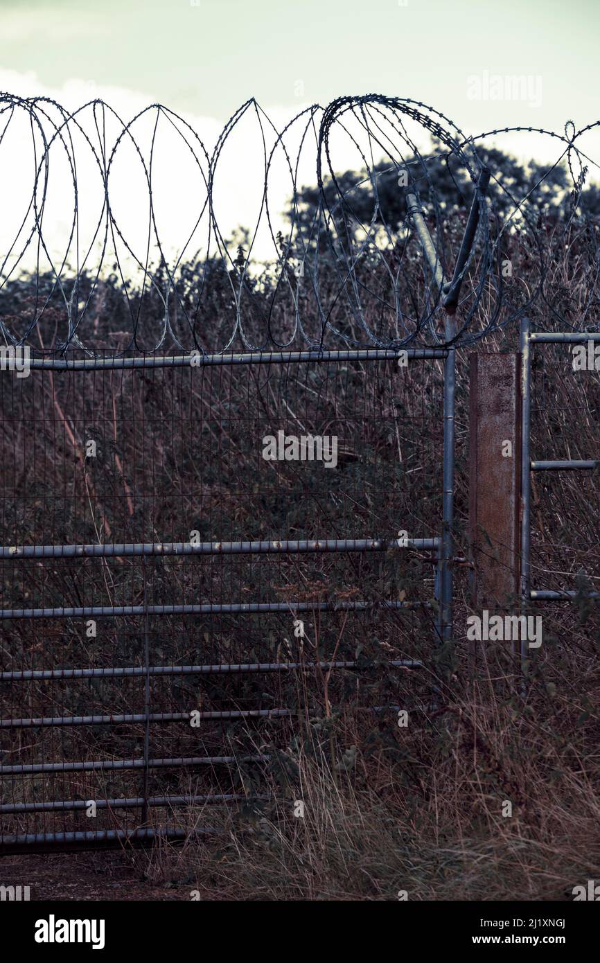 A high security fence with razor wire and barbed wire across the top ...
