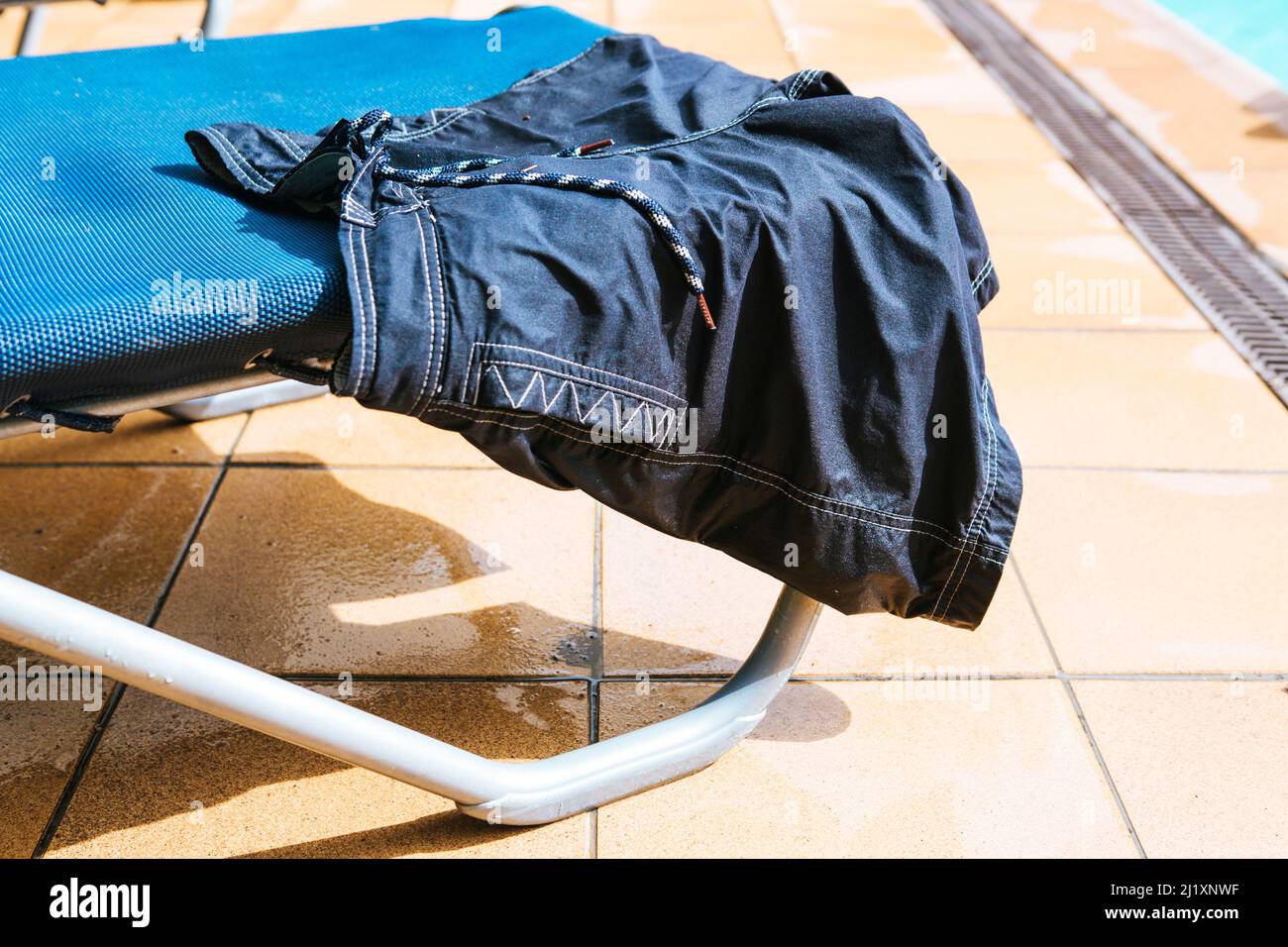 A pool side lounger with swimming costume, towels and rtrunks drying in the sun. Stock Photo