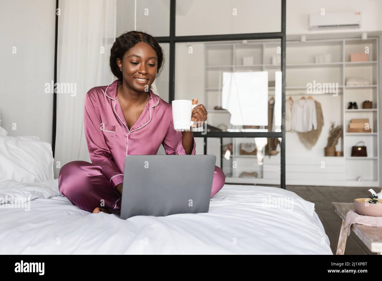 Happy African Lady Using Laptop And Drinking Coffee In Bedroom Stock ...