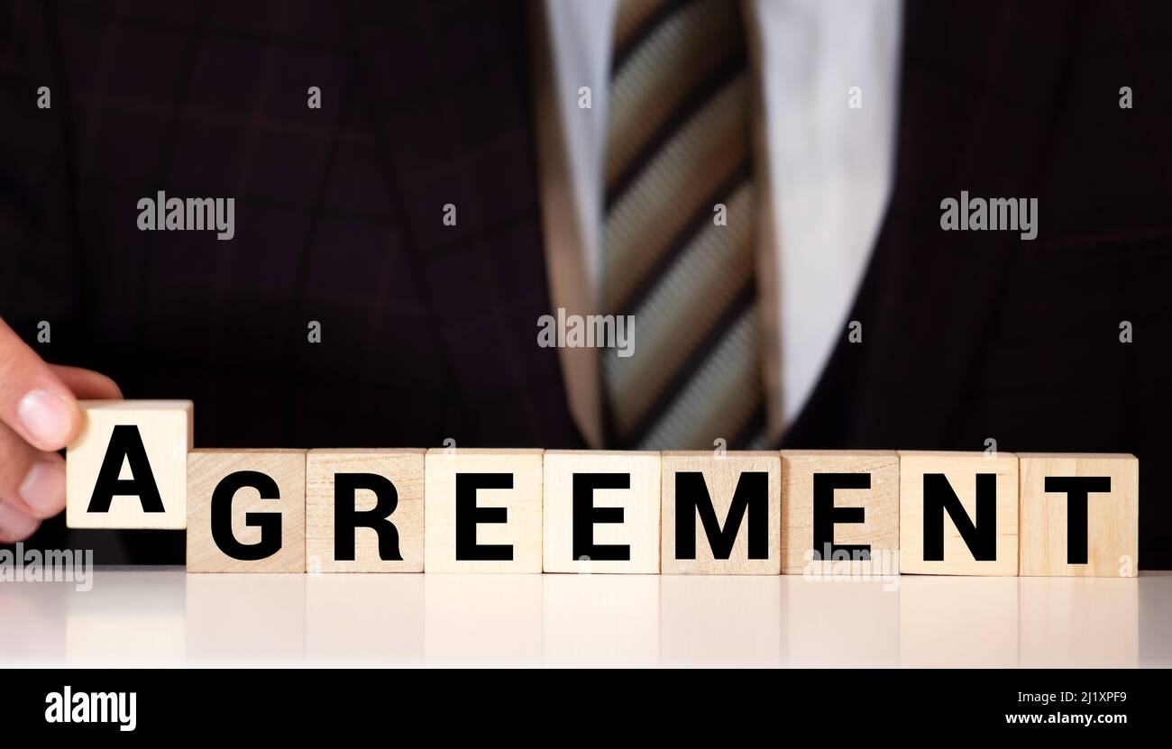 The word AGREEMENT written on wooden cube shape blocks on a contract background Stock Photo