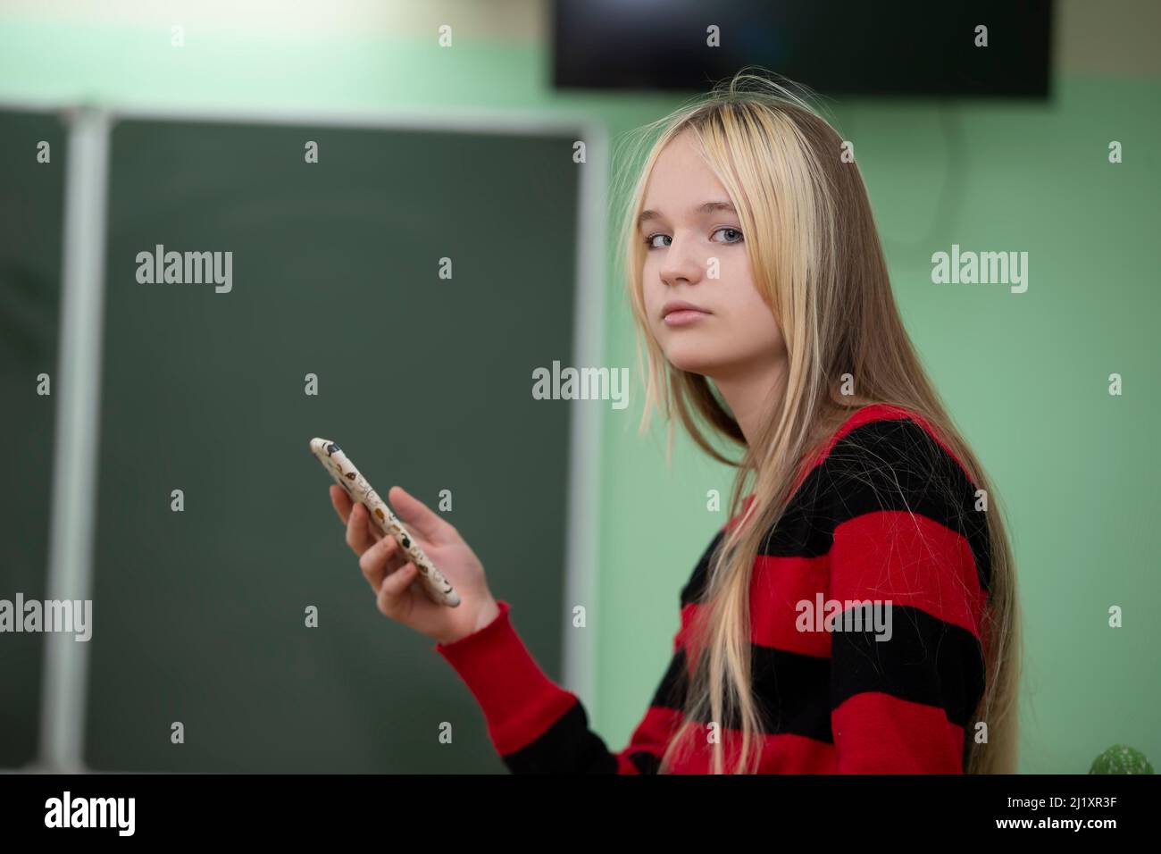 Teenager of senior school age. A teenage girl stands in front of a blackboard. Stock Photo