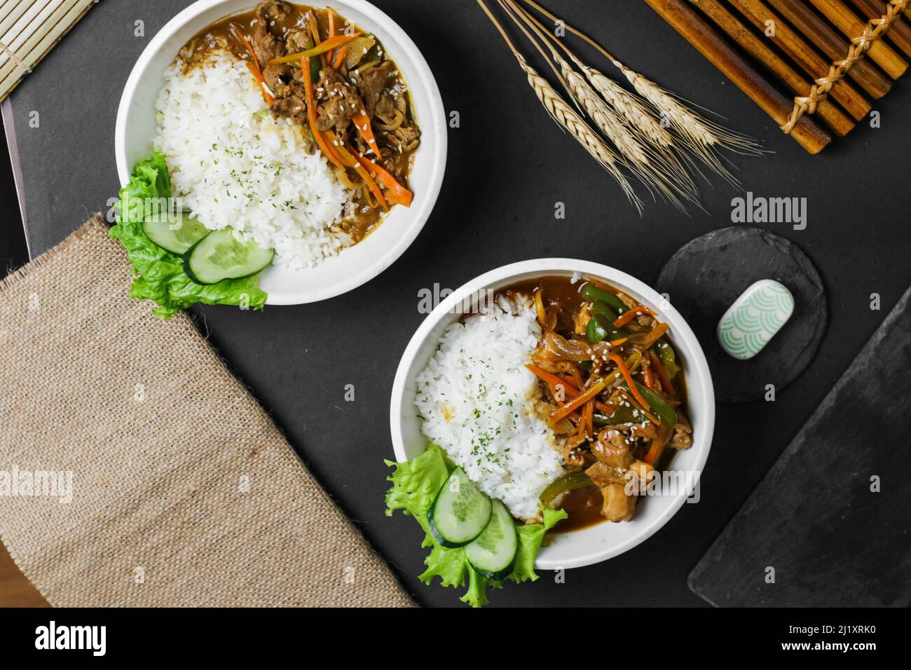 A top view of two portions of Japanese meals with boiled white rice