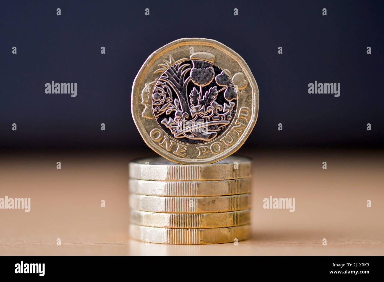 British one pound coin standing on its edge on top of a column of coins. No people. Stock Photo