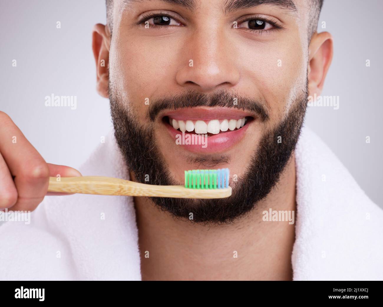 Remember to use circular motions. Shot of a handsome young man brushing his teeth against a studio background. Stock Photo