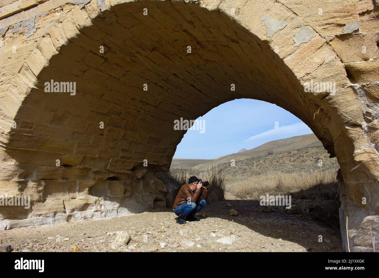 Gobustan. Azerbaijan. 03.07.2020 year. A photographer takes pictures of the old bridge over the river. Stock Photo