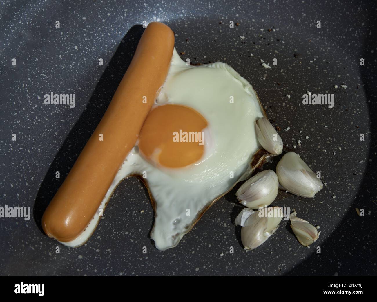 Preparing Breakfast in Cooking pan with Fried egg, Fried sausages and Garlic. Space for text, Selective focuse. Stock Photo