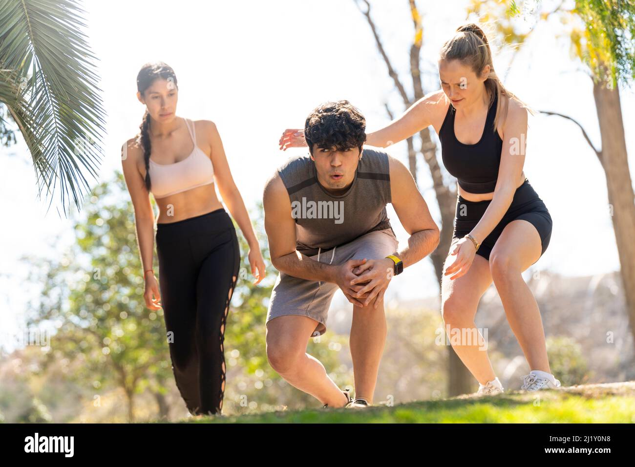 Two women help a man with an injured knee in the park Stock Photo