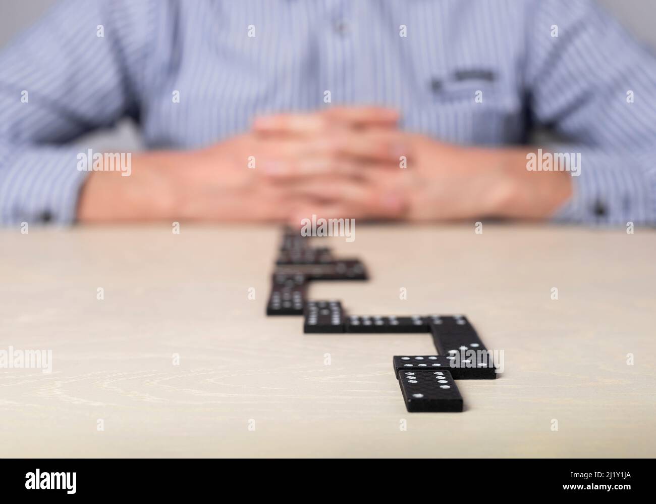 Businessman sitting at table with domino and thinking of action plan