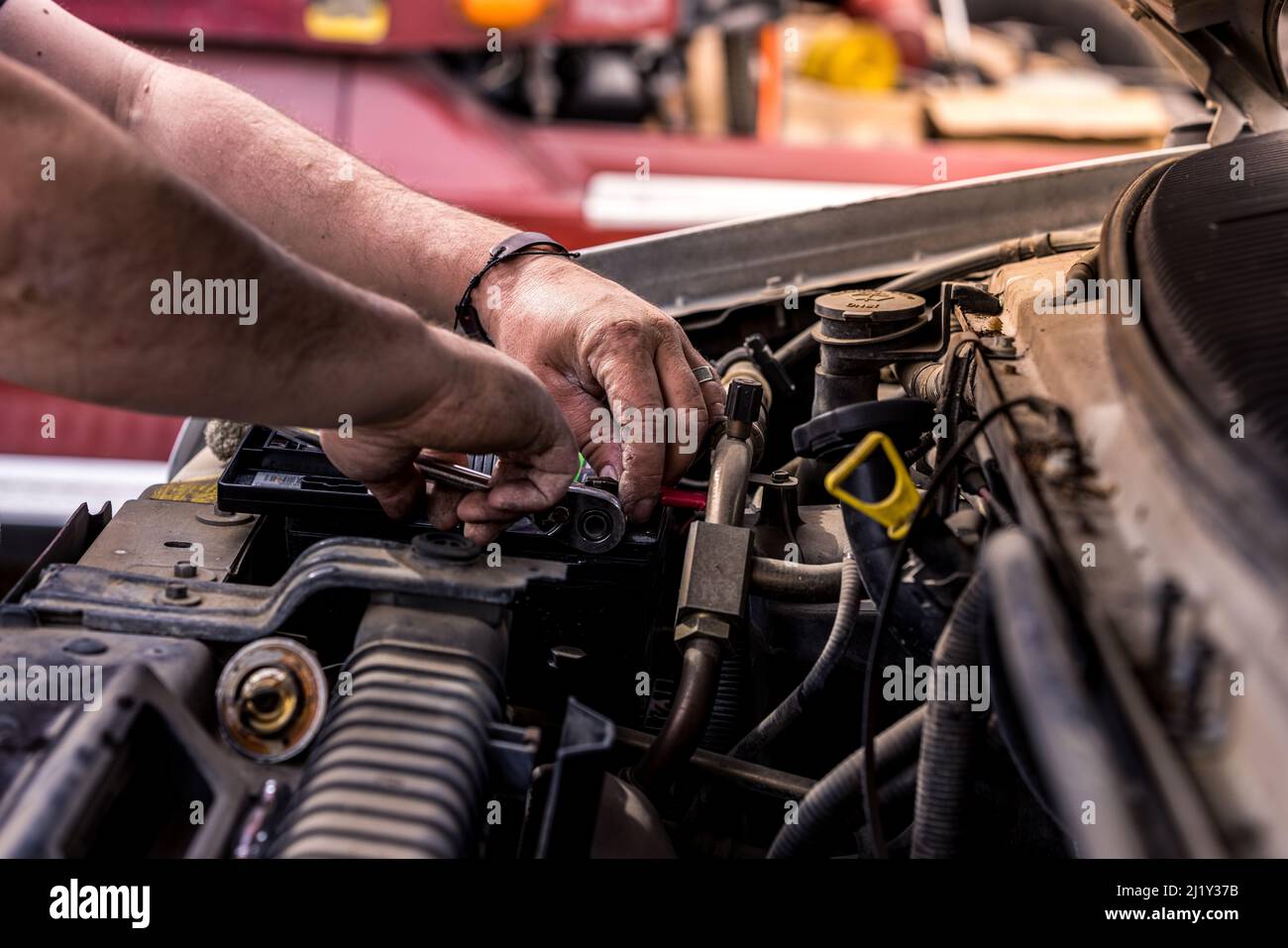 Mechanic with dirty hands works on car engine. Authentic shot of real auto mechanic working on motor. Stock Photo