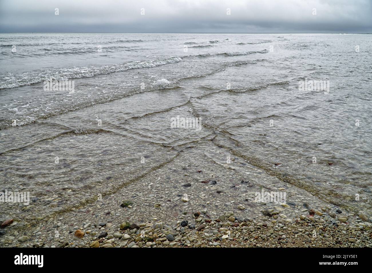 Overlapping, intersecting waves on seashore with dramatic cloudy sky. Natural background, pattern, texture of water. Interference of waves. Baltic Sea Stock Photo