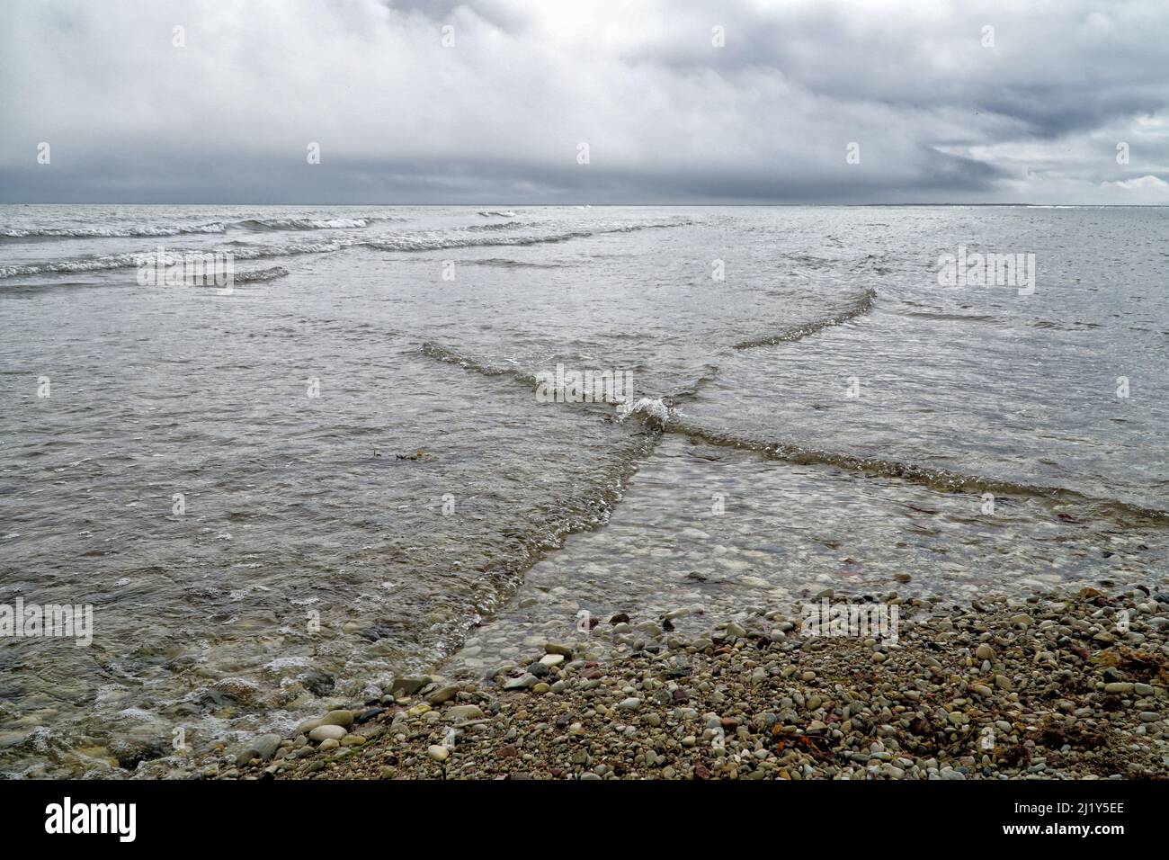 Overlapping, intersecting waves on seashore with dramatic cloudy sky. Natural background, pattern, texture of water. Interference of waves. Baltic Sea Stock Photo