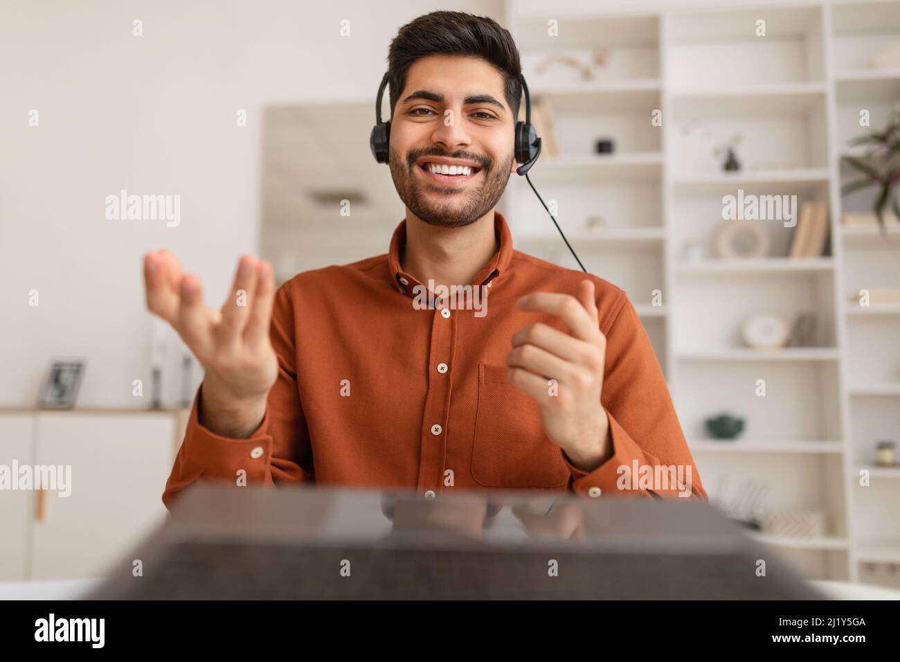 Arab man using laptop wearing headset sitting at desk Stock Photo