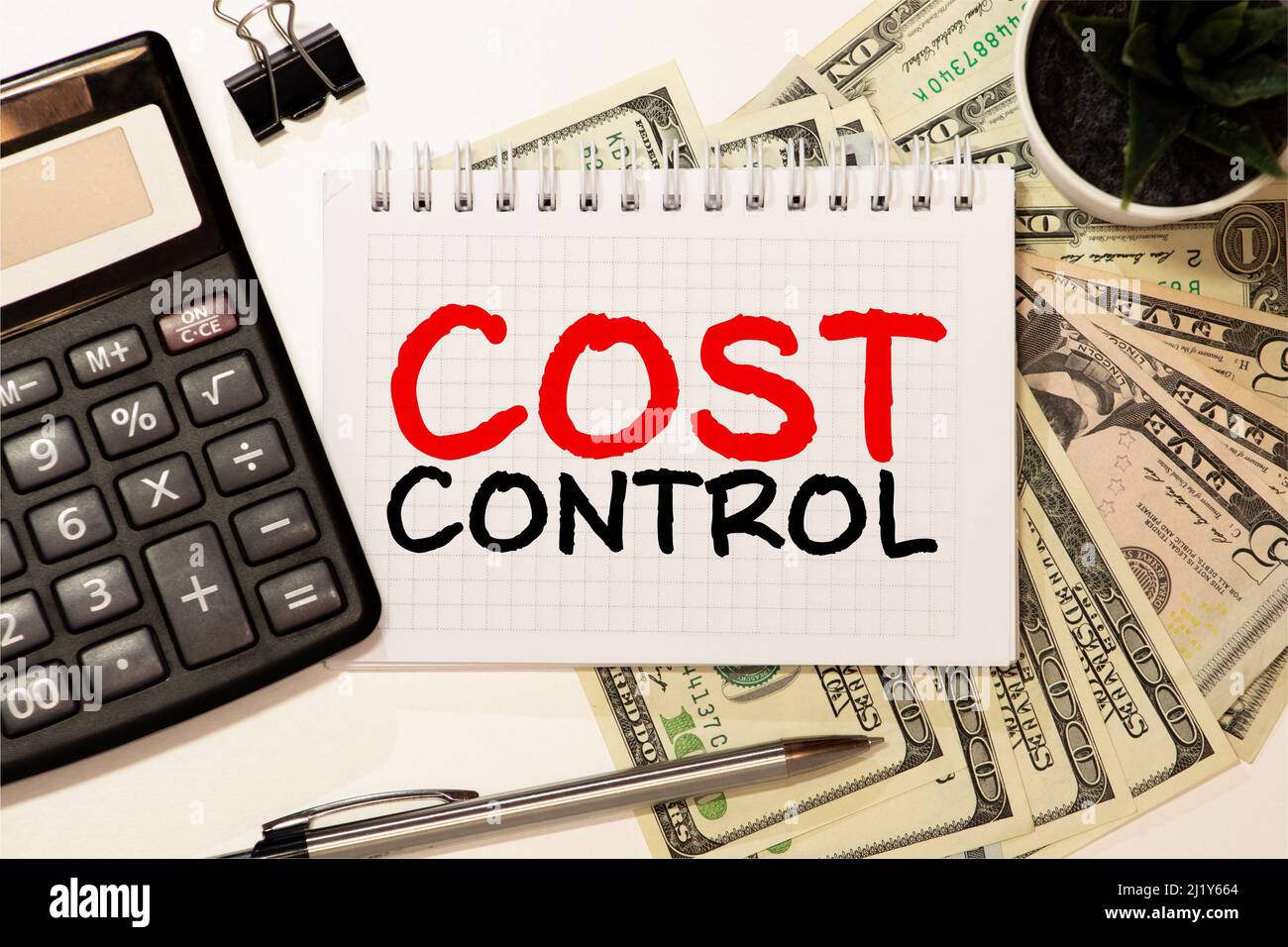 COST CONTROL. Black notebook and computer keyboard on a white office desk. Stock Photo