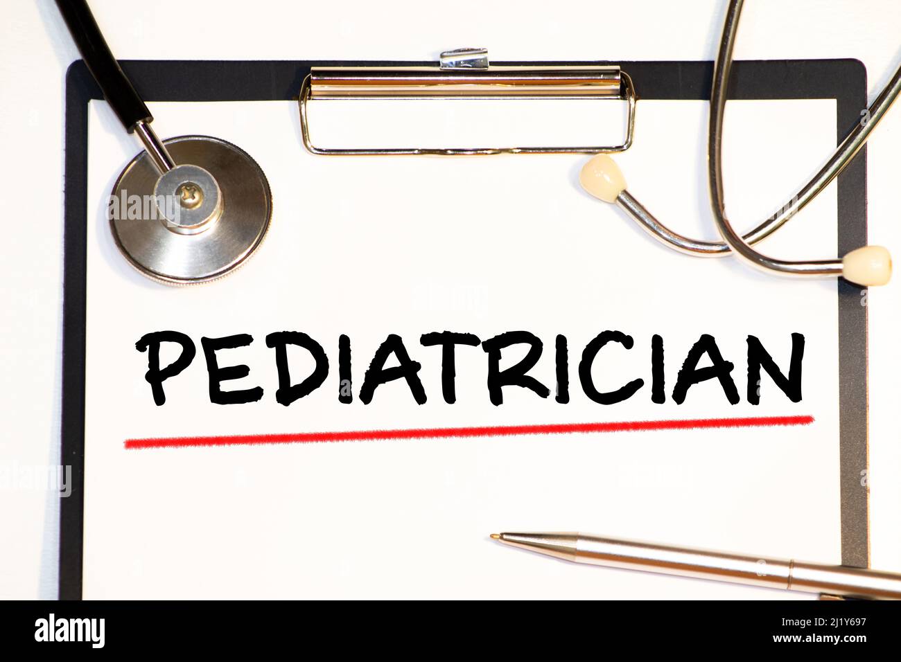 a doctor sitting in a desk with a injured teddy bear and a nameplate with the word paediatrician written in it. Stock Photo