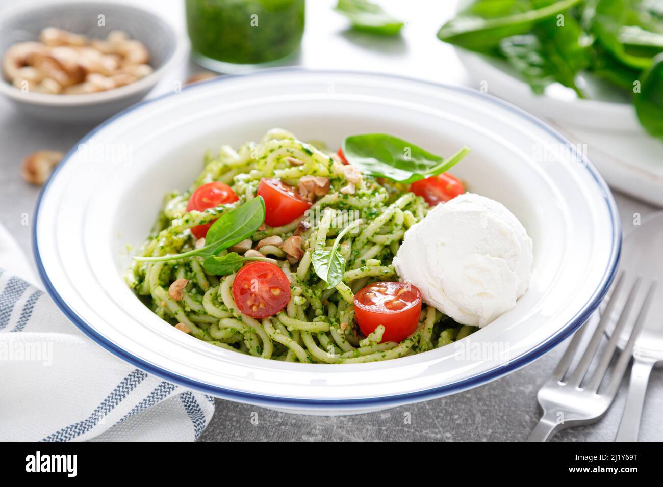 Pasta with spinach pesto, cashew nuts and soft cream cheese Stock Photo