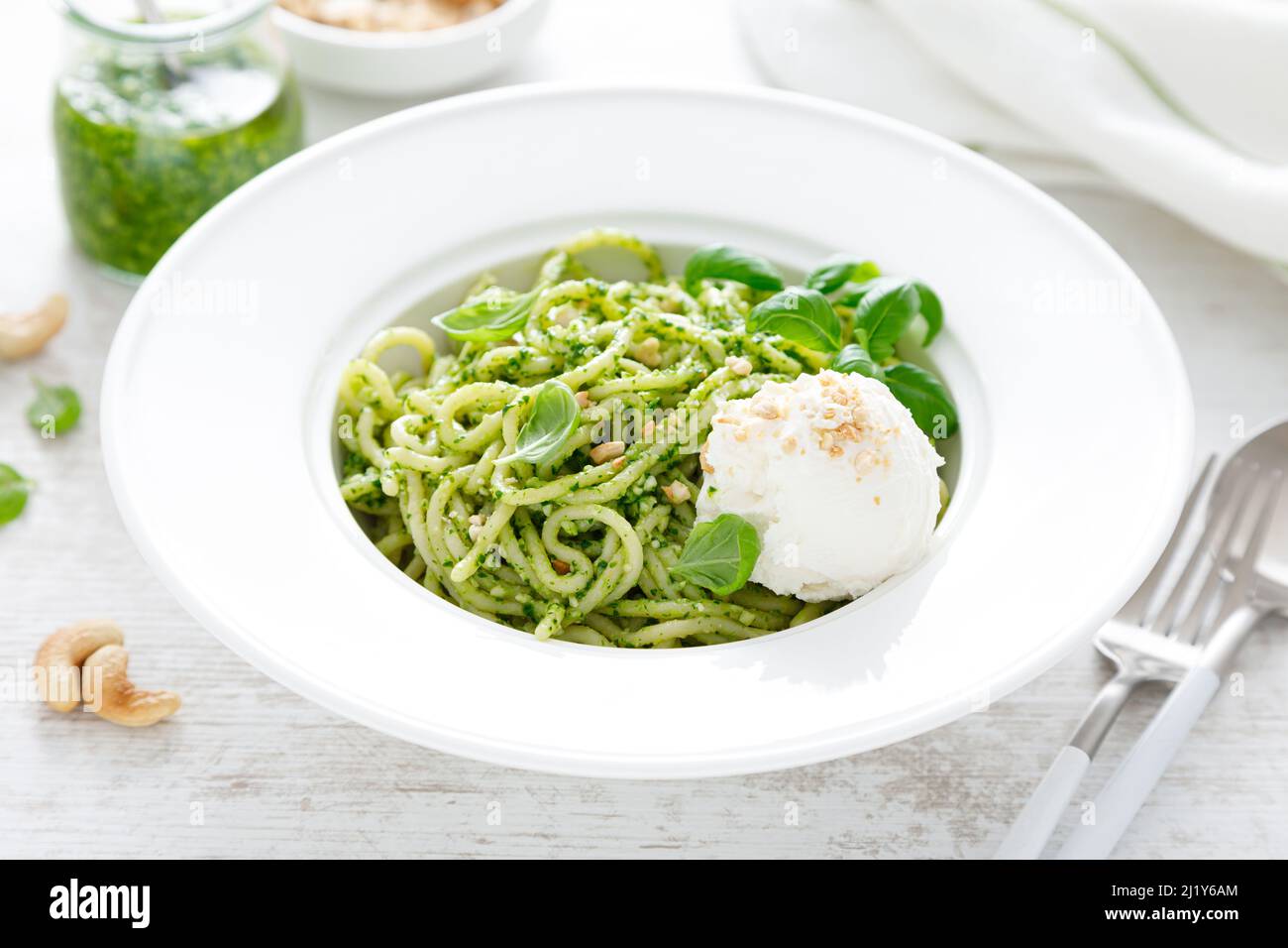 Pasta with basil pesto, cashew nuts and soft cream cheese Stock Photo