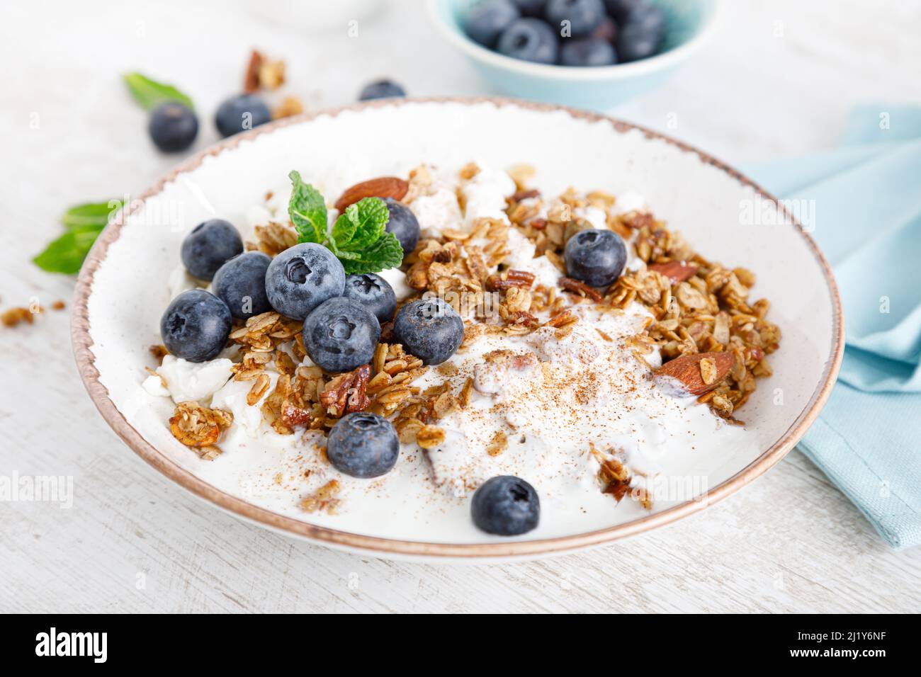 Bowl of granola with fresh blueberry, cottage cheese or curd, yogurt and nuts. Healthy food. Breakfast Stock Photo
