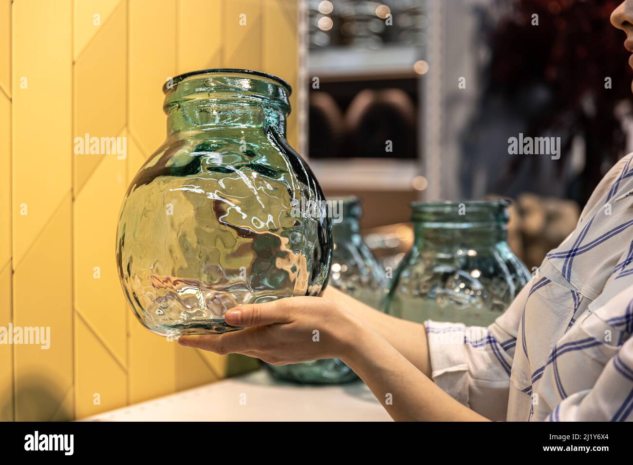Close-up, a glass jar in female hands on a shop window. Stock Photo