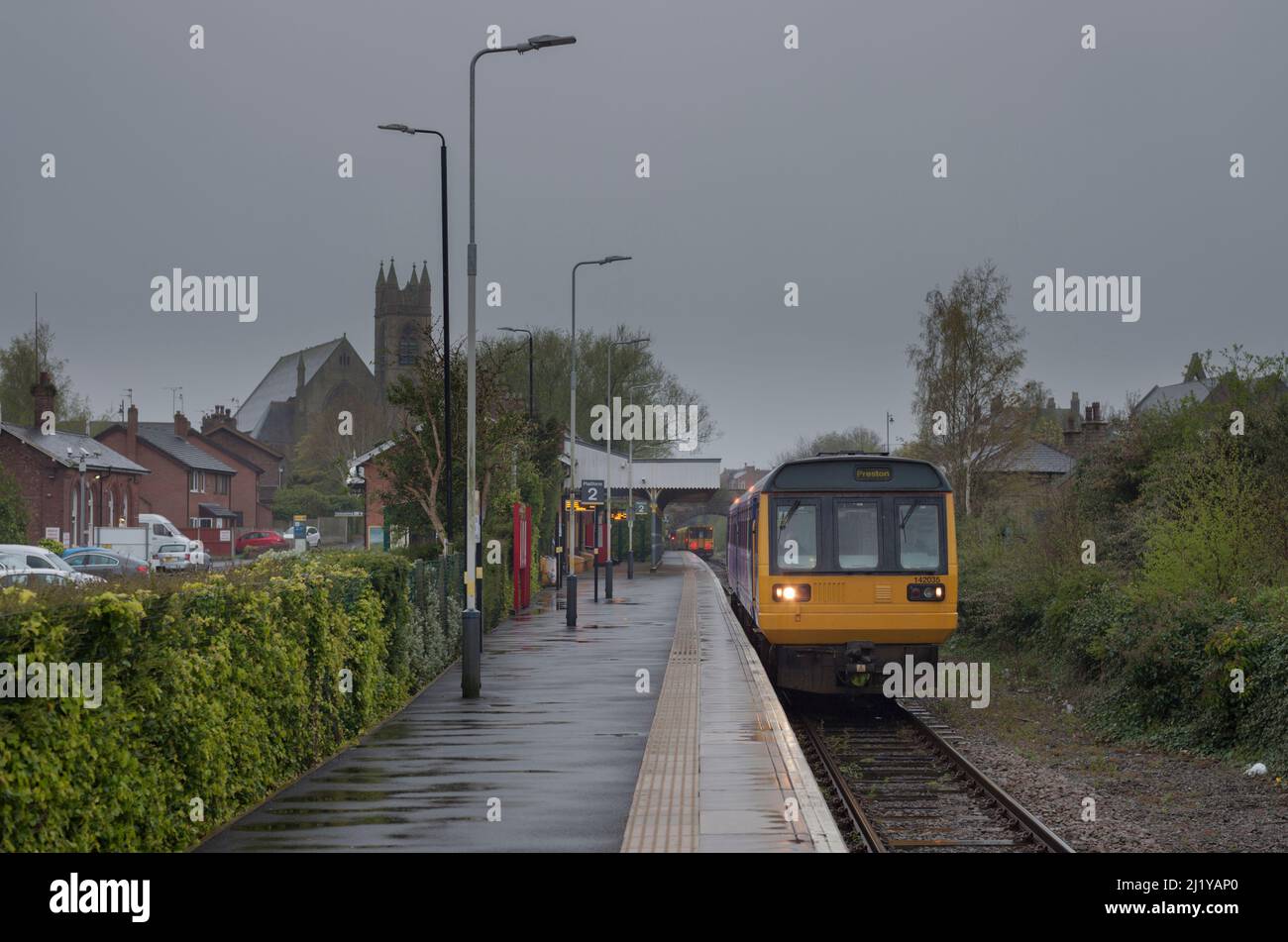An Arriva Northern rail class 142 pacer train 142035 at a wet Ormskirk railway station, Lancashire waiting to depart. Stock Photo