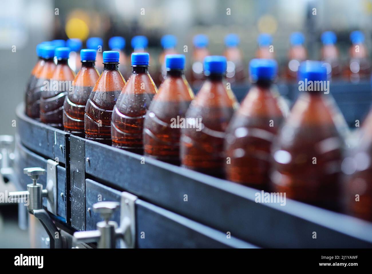 Plastic beer bottles on a conveyor belt in the background of a brewery