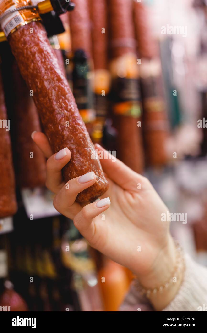 Woman chooses dried smoked sausage hanging in refrigerator in butcher's shop Stock Photo Alamy