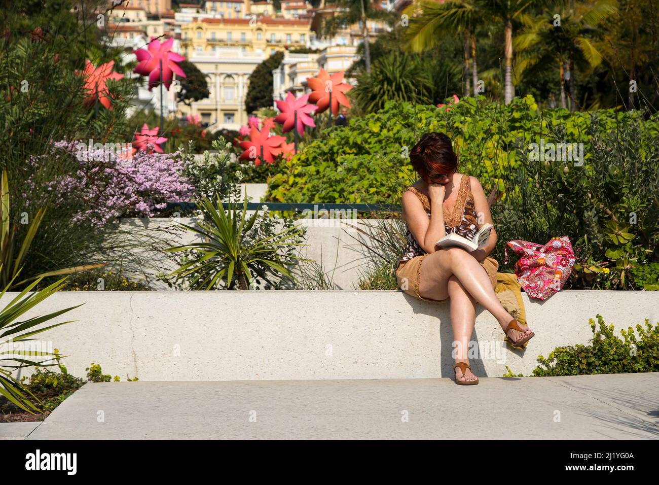 Monte-Carlo, Monaco. 28 Mar 2022 - A woman reads a book in Casino Square, Monte-Carlo on a sunny and warm day. Credit Dinendra Haria /Alamy Live News Stock Photo