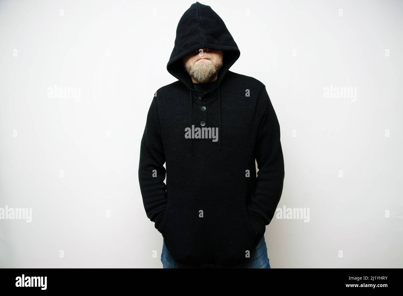 Man with a serious blond beard and a hooded sweater covering half of his face on a light background Stock Photo