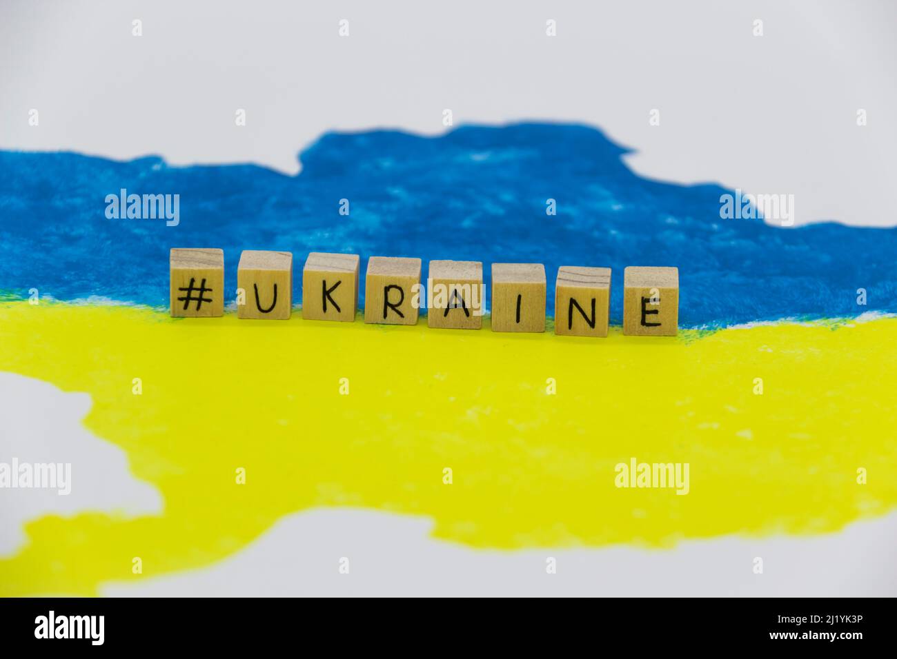 The word Ukraine written on wood cubes on background with Ukrainian map in blue and yellow colors Stock Photo