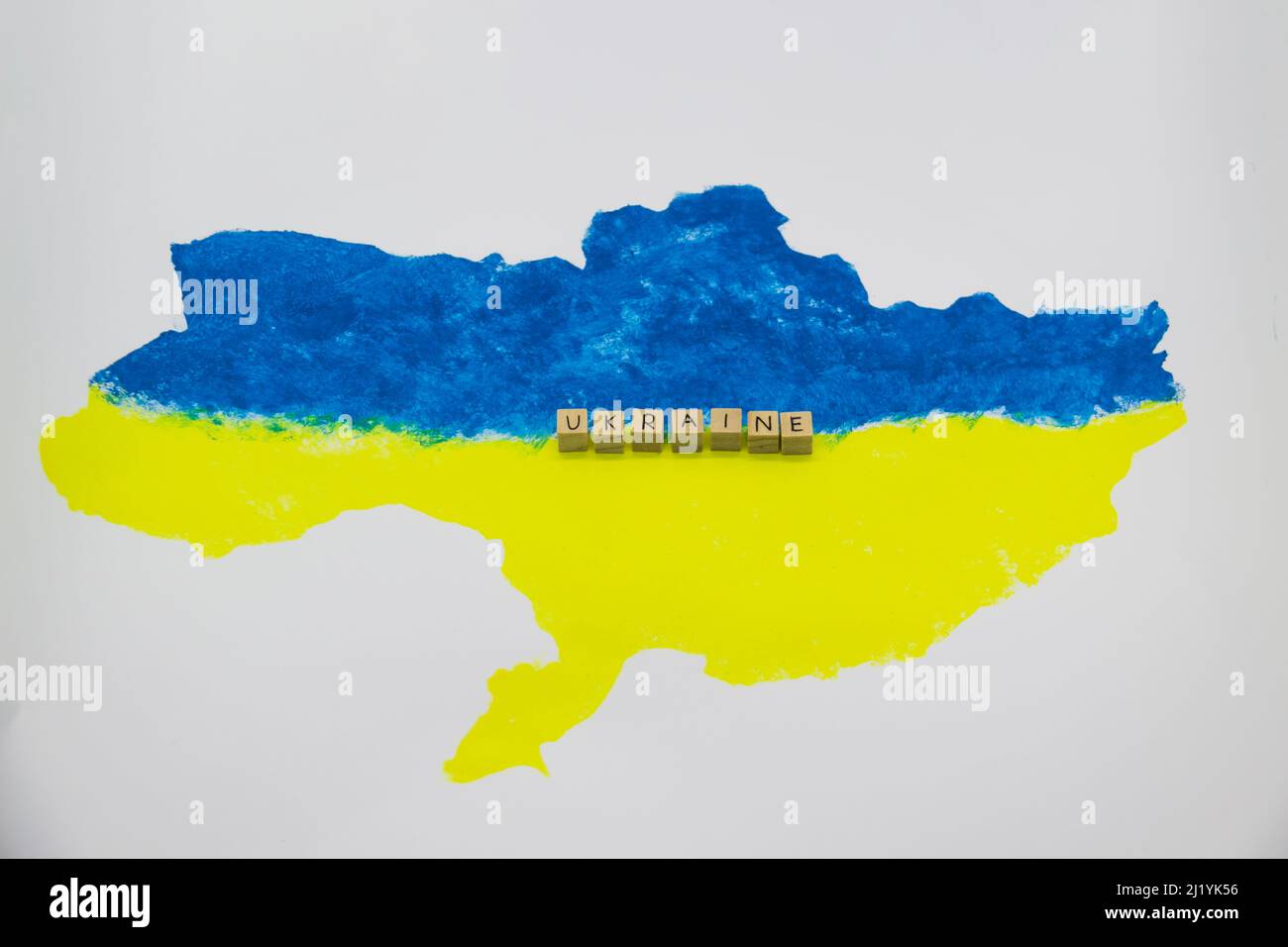The word Ukraine written on wood cubes on background with Ukrainian map in blue and yellow colors Stock Photo
