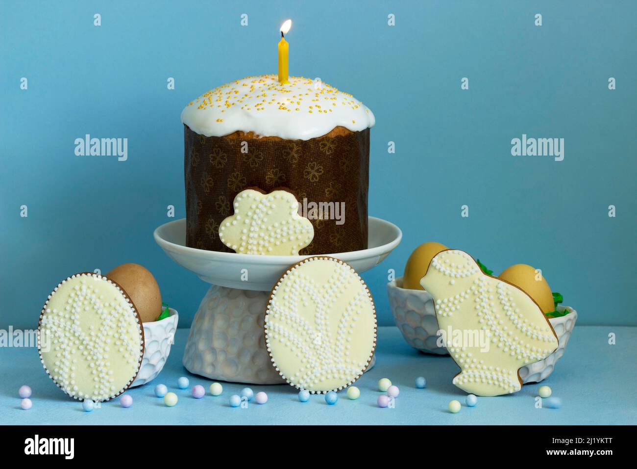 Easter composition, traditional Easter cake, colored eggs and gingerbread on a blue background. Stock Photo