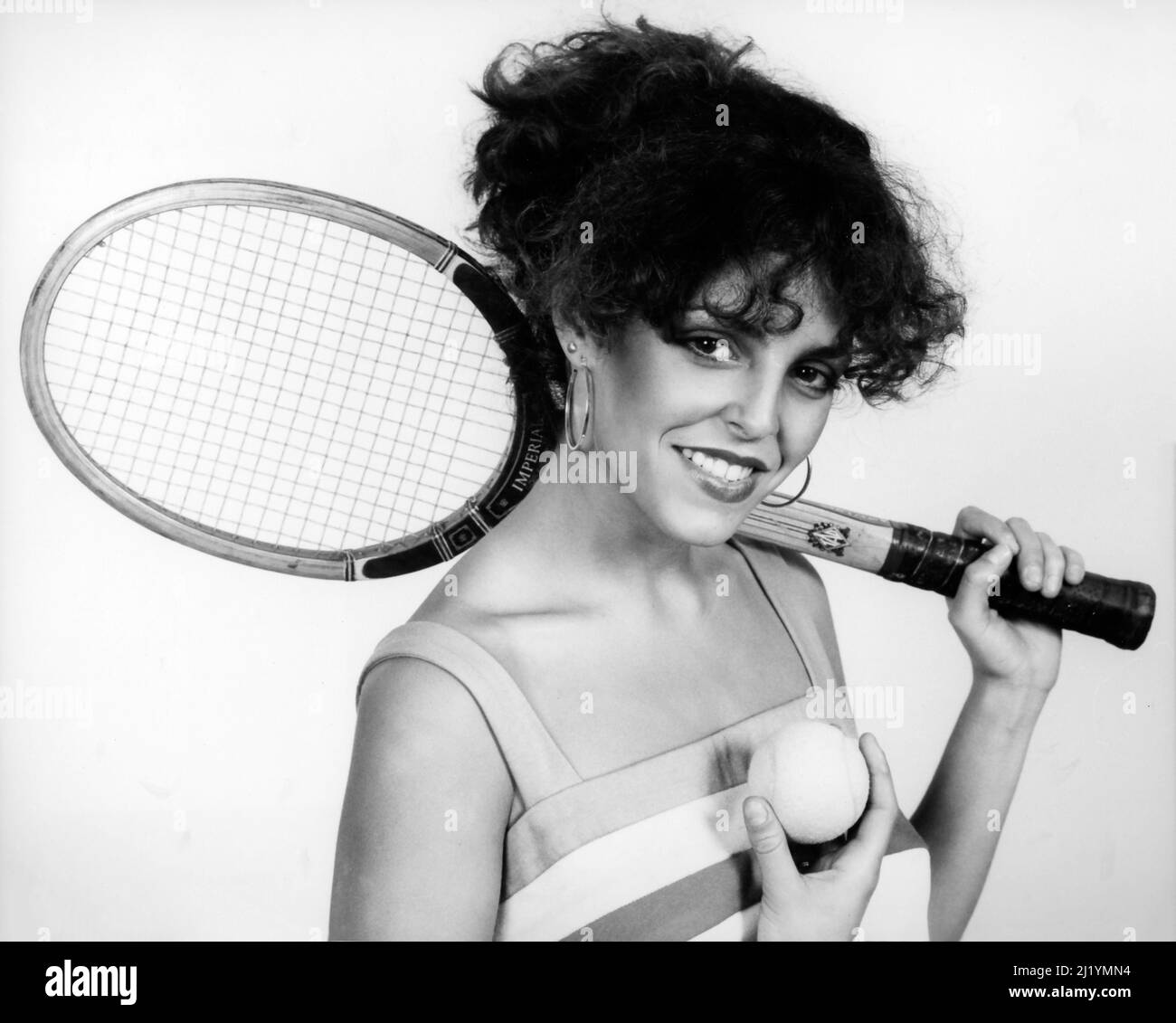 Studio portrait of young girl with wooden tennis racket and ball circa 1980s Stock Photo