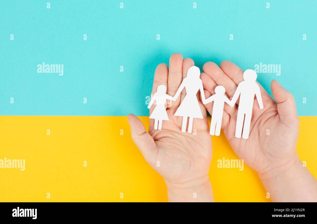 Parents with two child holding hands, family life, paper cut out, copy space, yellow and blue colored background, relationship Stock Photo