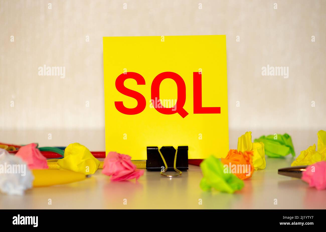 The SQL label on the yellow business card from the daily planner. The blue diary and yellow pen are on the orange table. Stock Photo