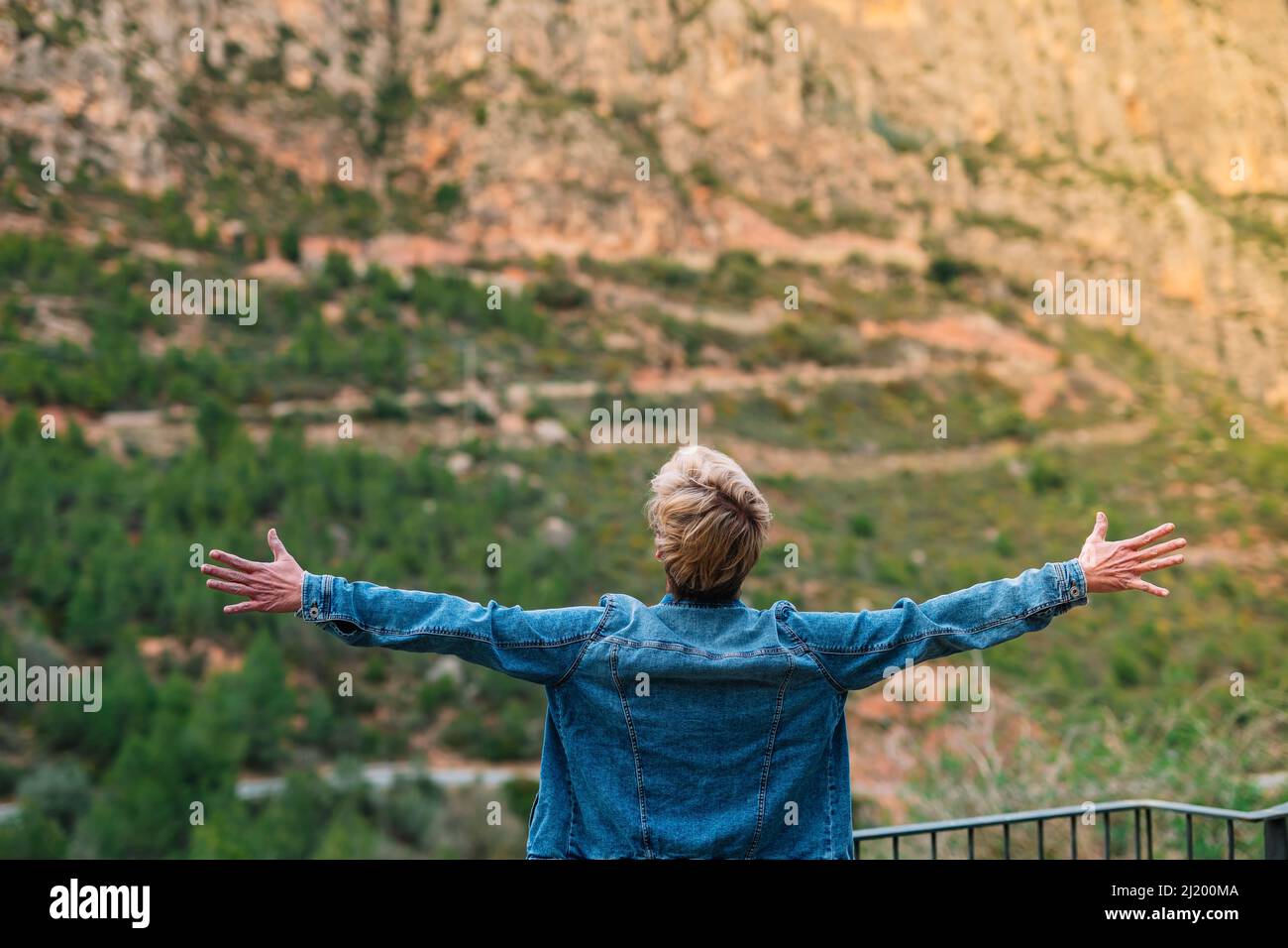 adult blonde short haired woman on holiday enjoying the scenery with her arms outstretched. Stock Photo