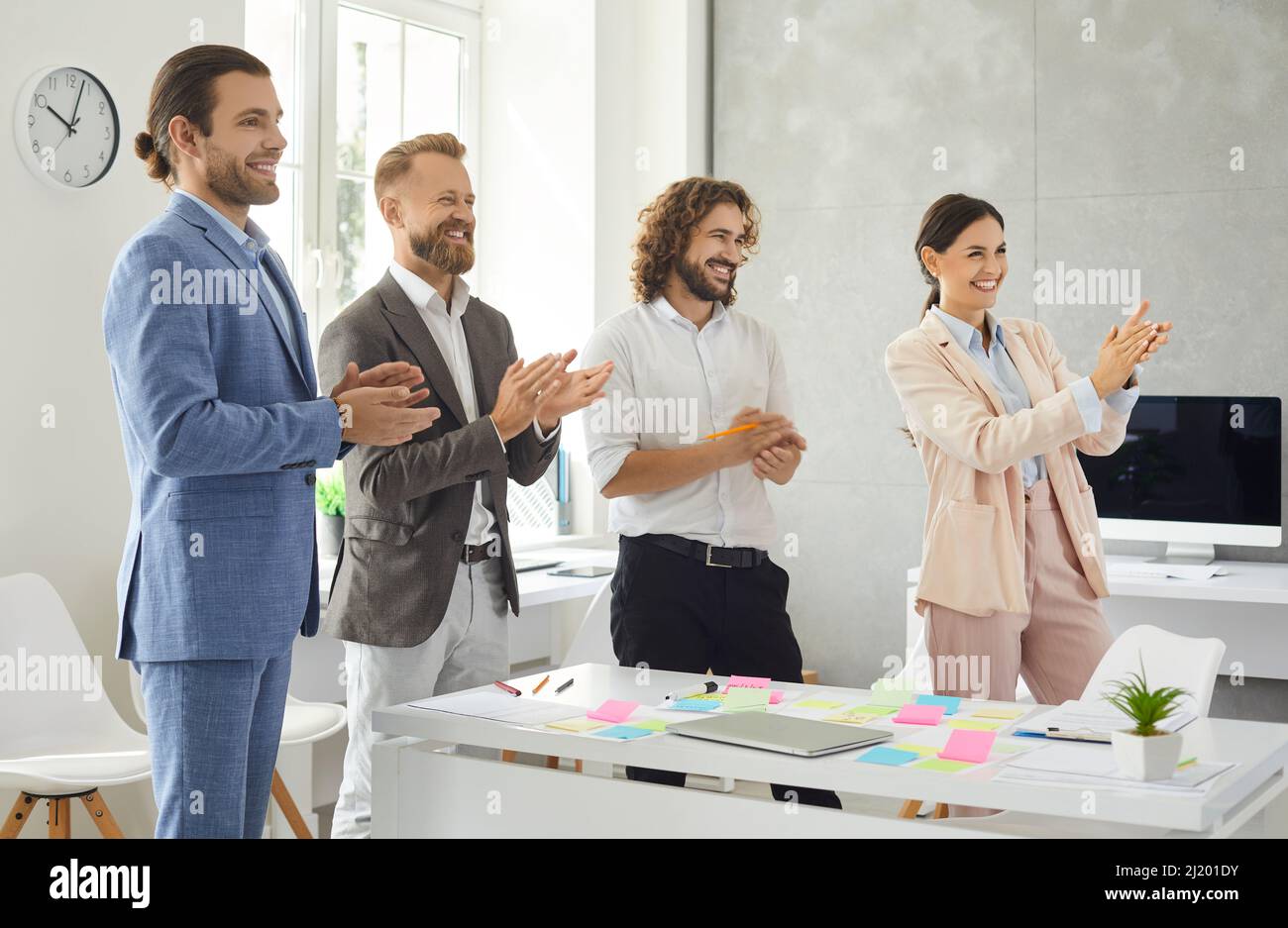 Smiling multiethnic employees applaud congratulate coworker with success Stock Photo