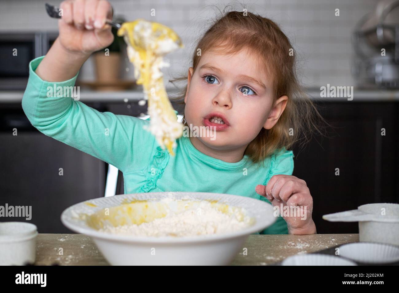 Small happy child cooking in kitchen. Little beautiful girl making
