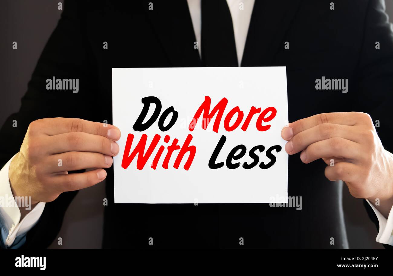 The words Do More With Less on a card pinned to a cork notice board as ...