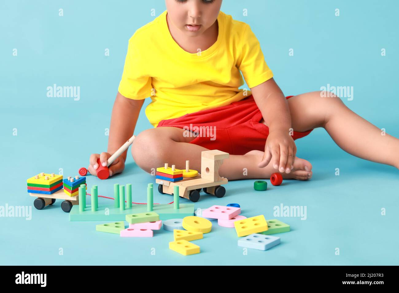 Cute little boy playing with wooden toys on blue background Stock Photo ...