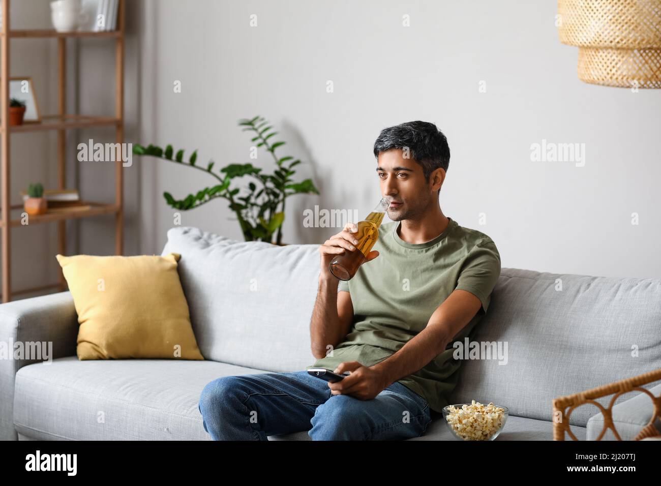 Handsome man drinking beer while watching TV at home Stock Photo