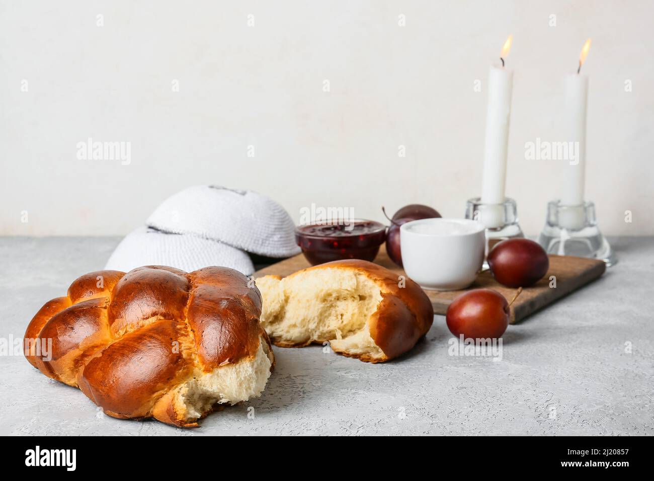 https://c8.alamy.com/comp/2J20857/traditional-challah-bread-with-glowing-candles-and-jewish-caps-on-light-background-shabbat-shalom-2J20857.jpg