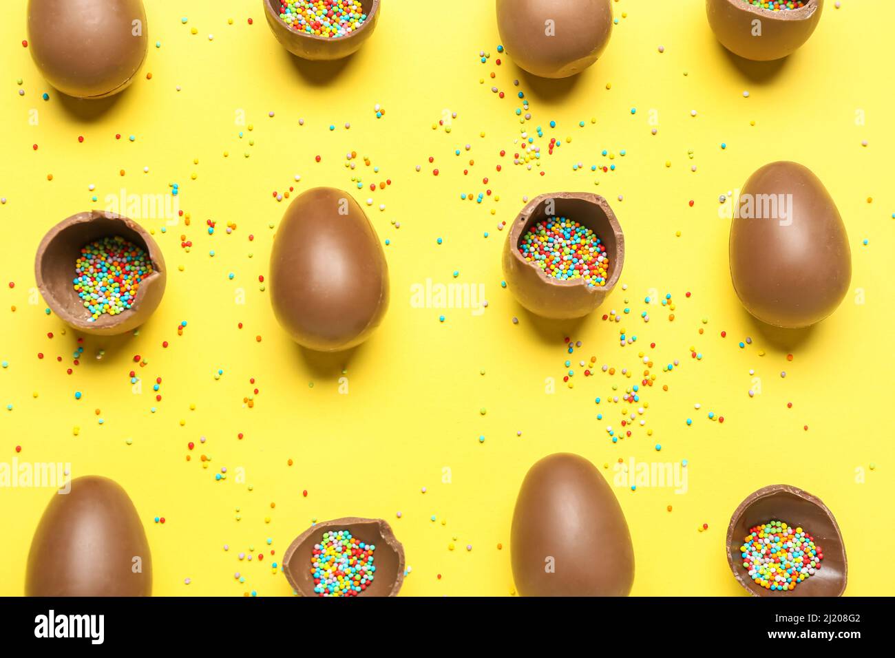 Delicious chocolate eggs with sprinkle fillings on yellow background