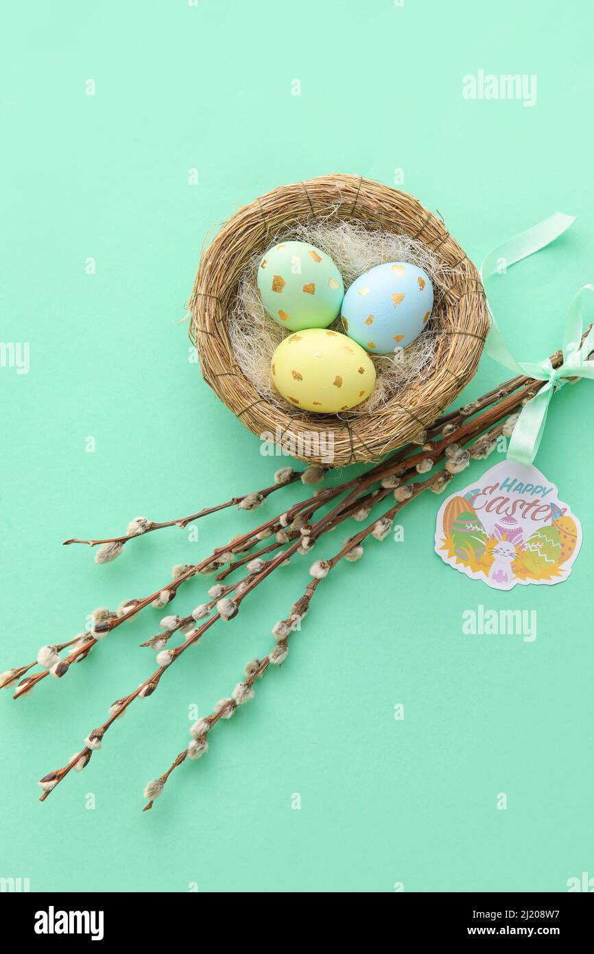 Nest with painted Easter eggs and willow branches on blue background ...