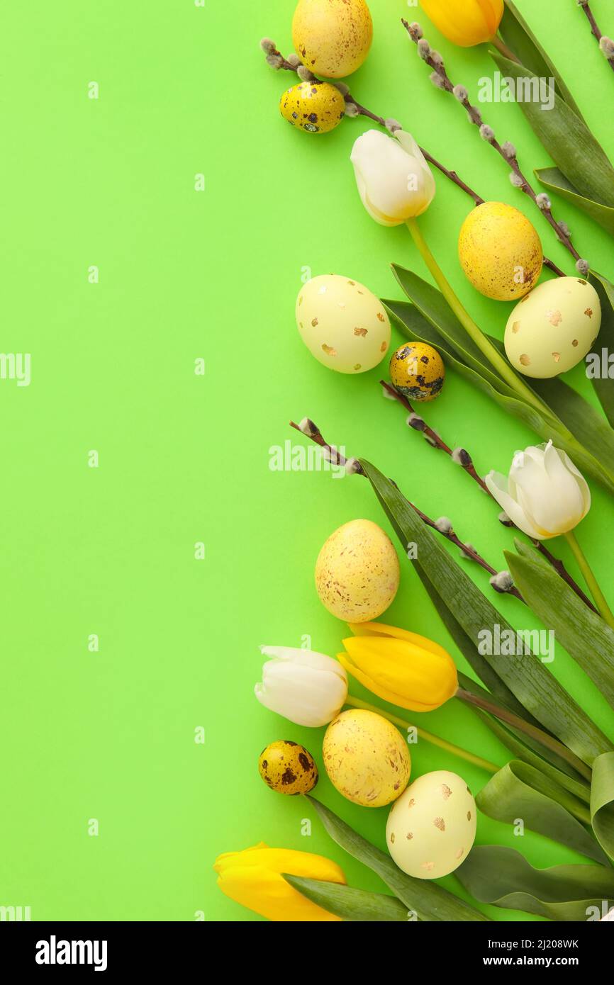 Painted Easter eggs, tulip flowers and willow branches on green background Stock Photo