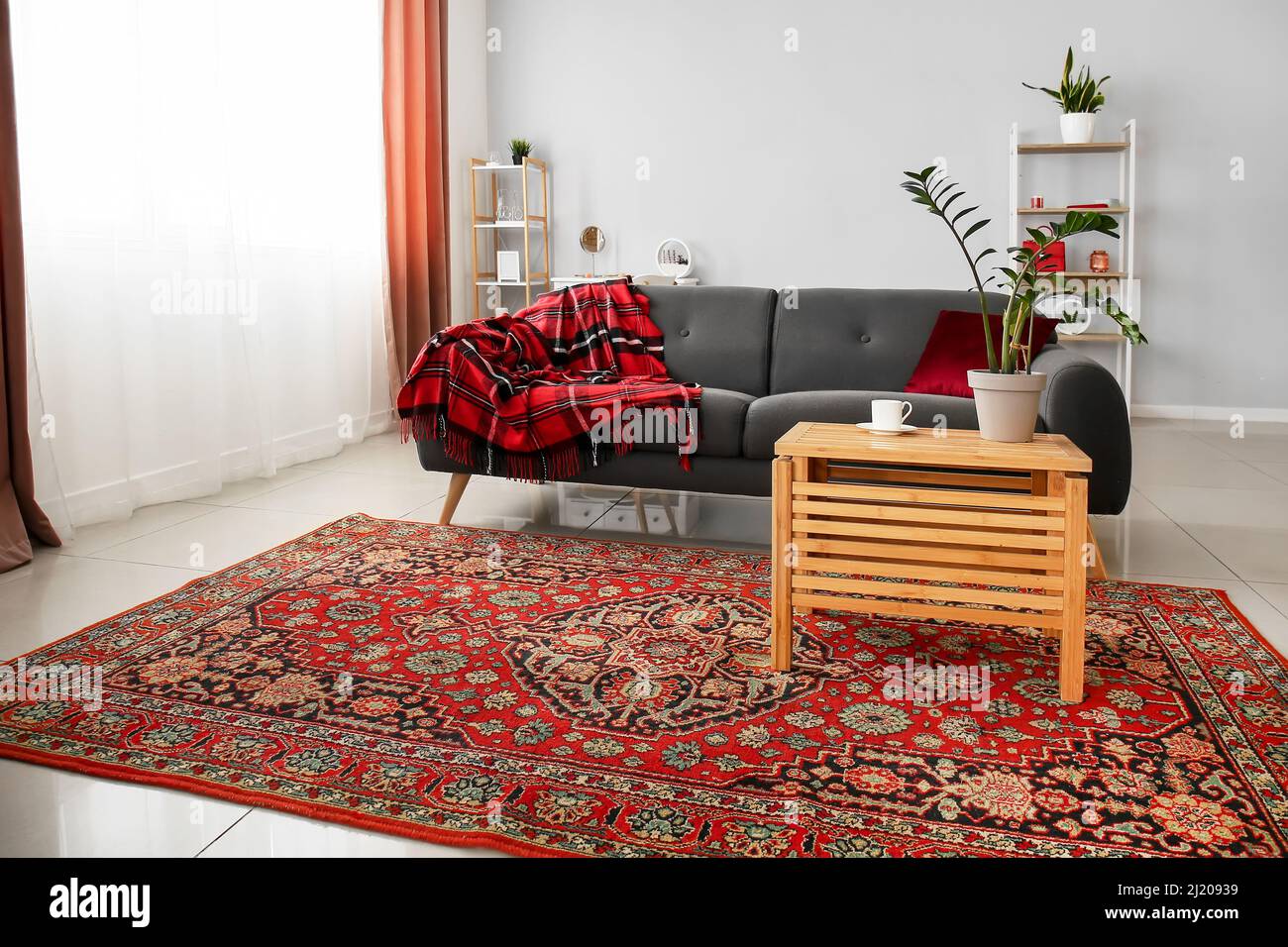 Interior of cozy living room with vintage carpet, table and sofa Stock