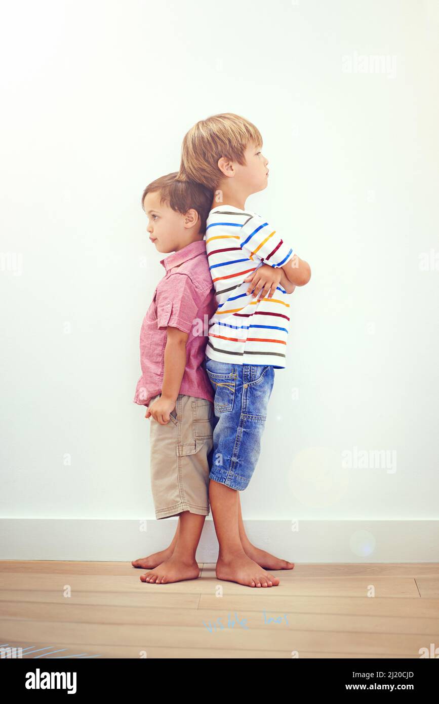 Little brother, big brother. Two little boys standing back to back. Stock Photo