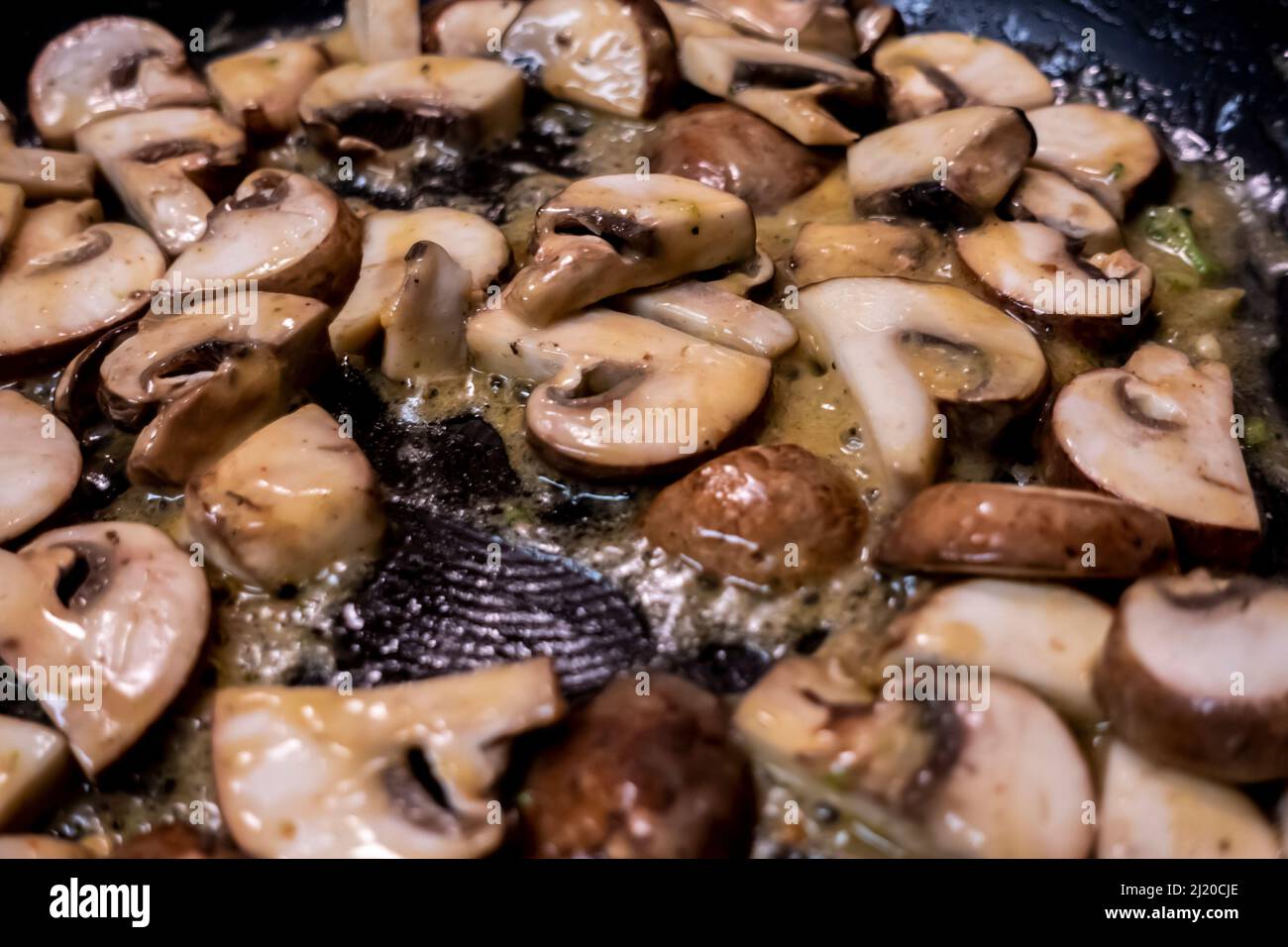 Macro, selective focus on baby bella mushrooms cooking in a large