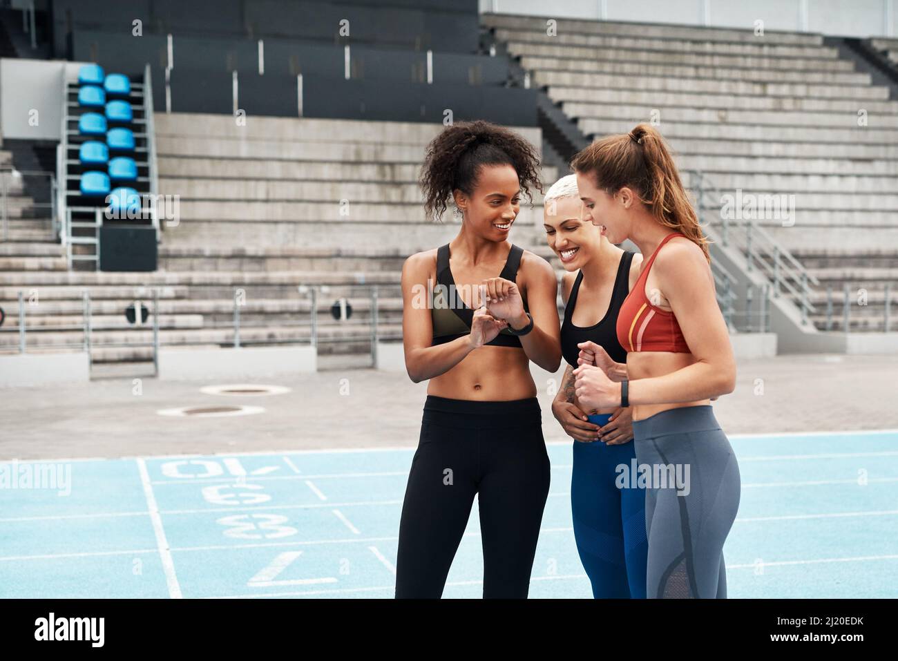 We constantly challenge each other. Cropped shot of an attractive young group of athletes standing together and comparing times after an outdoor Stock Photo