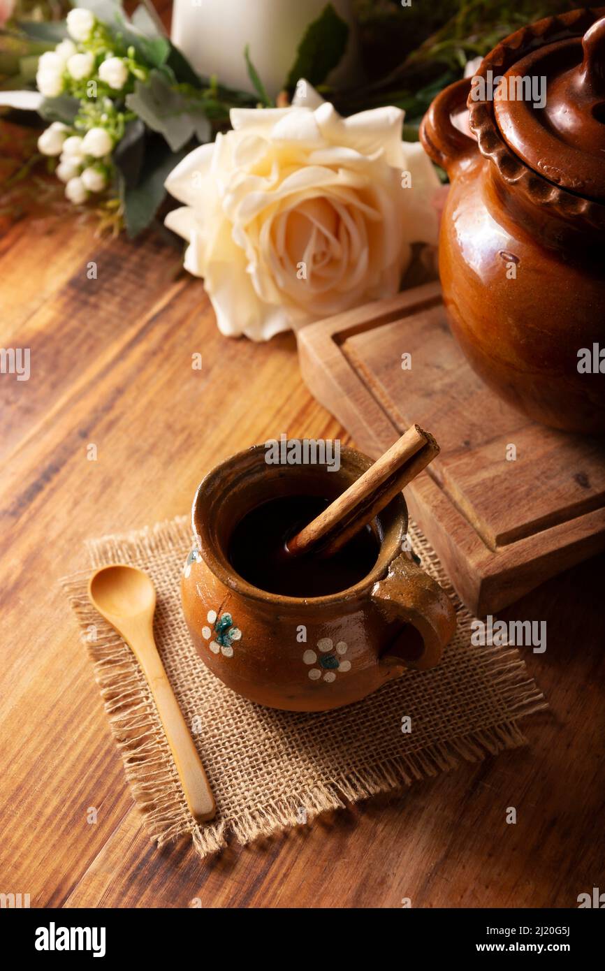 Authentic homemade mexican coffee (cafe de olla) served in traditional clay mug (Jarrito de barro) on rustic wooden table. Stock Photo