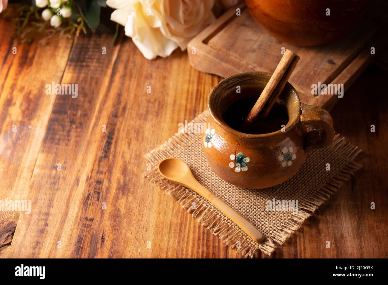 Authentic homemade mexican coffee (cafe de olla) served in traditional clay mug (Jarrito de barro) on rustic wooden table. Stock Photo